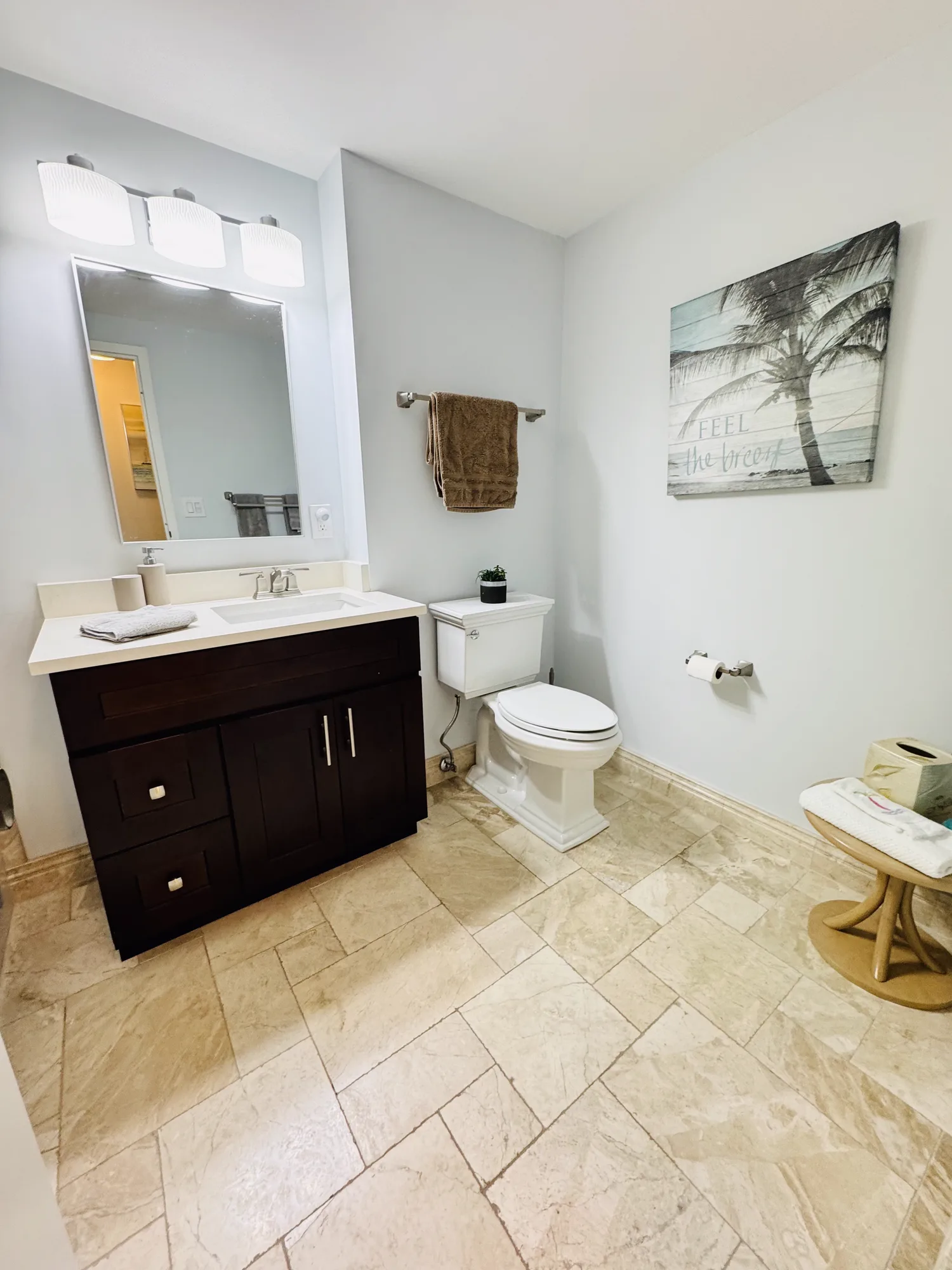 Bathroom with a dark wood vanity, a white sink, a mirror, and a framed beach print on the wall.