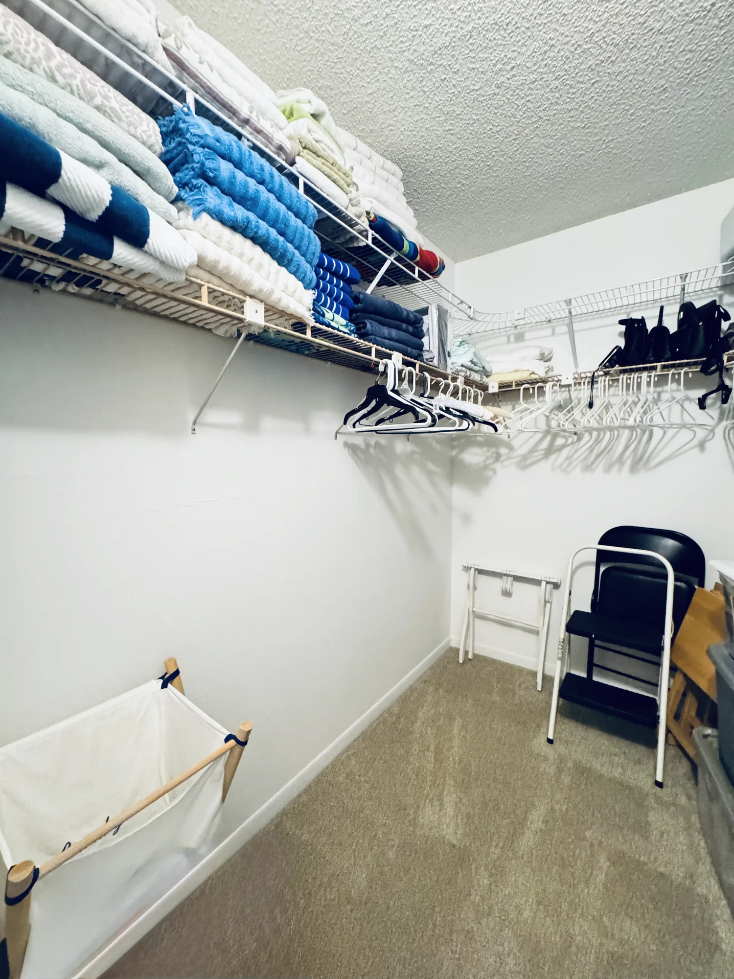 Linen closet with shelves of folded towels and bedding, and hanging space below.