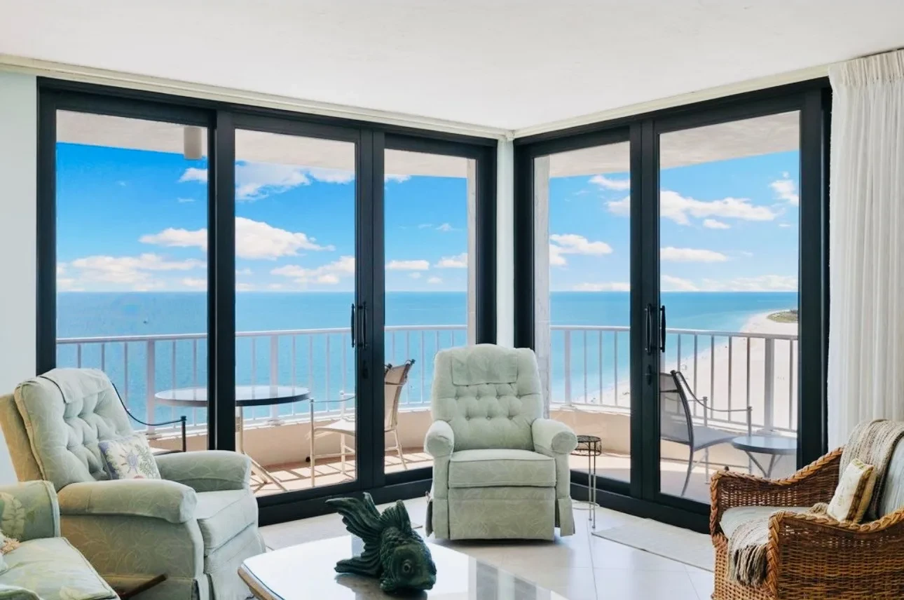 Living room at the Royal Seafarer with floor-to-ceiling glass on two sides and the Gulf filling the windows.